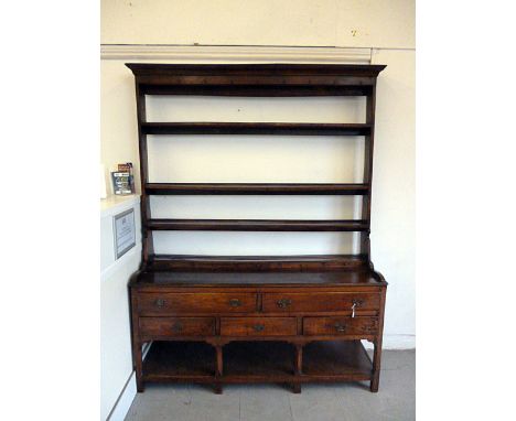 An 18th century English oak dresser, with an open back delft rack surmounting a two long over three short drawer pot shelf ba