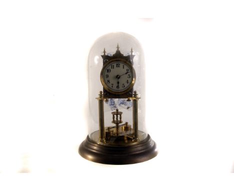 A brass mantle clock under dome, the brass timepiece having black Arabic numerals to white face, under glass dome, with key, 