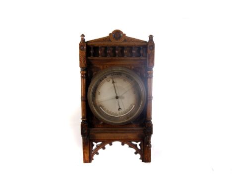 An aneroid carved oak wall barometer, having decorative floral and architectural design, with cracked glass