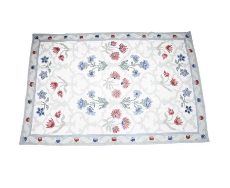 AN INDIAN CREAM GROUND FLAT WOVEN RUG, the large rectangular centre field filled with scattered flower heads in claret and li