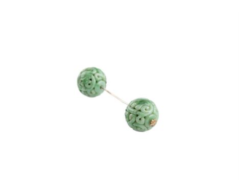 A CHINESE CARVED APPLE GREEN JADE HAT-PIN, formed as two pierced spheres, joined by a silver pin, each intricately carved wit