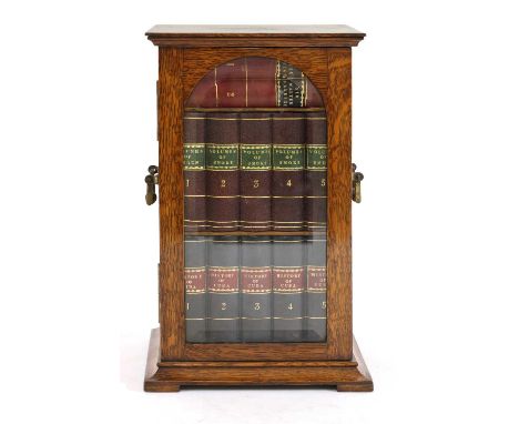 A Victorian oak novelty table/smoker's cabinet,the arched, glazed door enclosing three drawers fronted with leather faux book