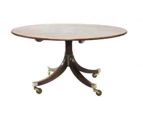 A George III mahogany circular dining table,c.1760, on a turned column support, sabre legs and oversized brass castors,142cm 