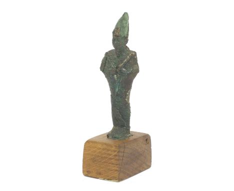 An ancient Egyptian bronze figure of Osiris,Third Intermediate Period, 9th century BCE, on a fitted oak plinth, bearing a man