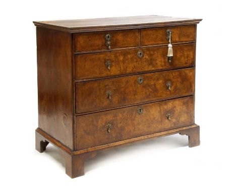 A Queen Anne walnut chest of drawers, early 18th century, with feather banded quarter veneer decoration, fitted two short and