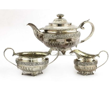 A George III three-piece silver tea set,by Naphtali Hart, London 1815,the teapot with an urn-shaped finial decorated in relie