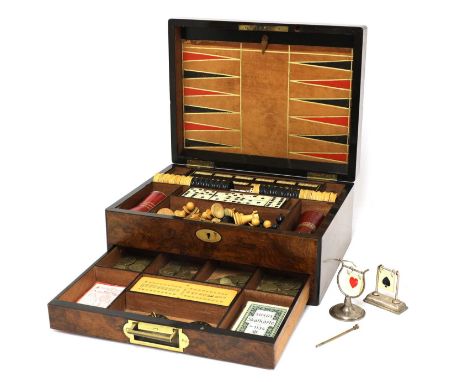 A Victorian walnut games compendium,containing a folding leather chess/backgammon board, a turned wooden chess set, draughts,