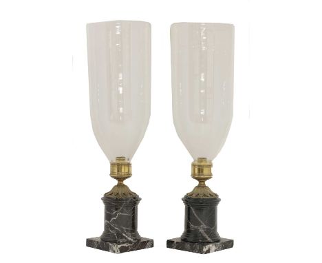 A pair of hurricane lamps, 20th/21st century, the glass shades supported by foliate brass mounts and raised on veined black m
