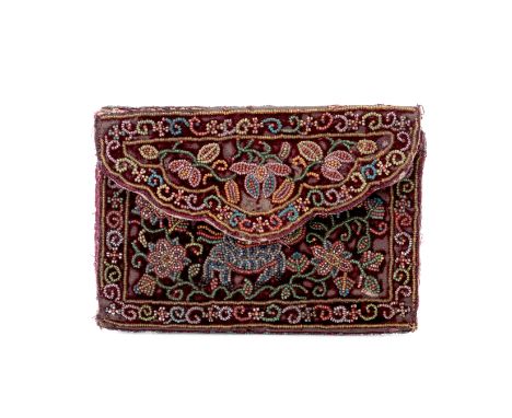 A BEADED VELVET PURSE
Of envelope form, the front decorated with a mythical beast amongst flowering foliage within a scroll b