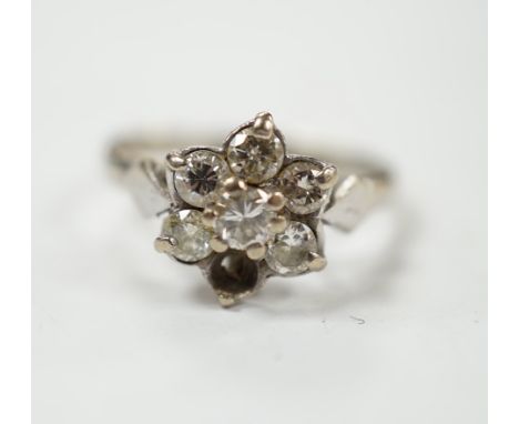 An 18ct white metal and seven stone diamond cluster set flower head ring (one stone missing), size K/L, gross weight 3.4 gram