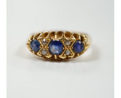 An early 20th century yellow metal, three stone sapphire and four stone diamond chip set half hoop ring, size P, gross weight