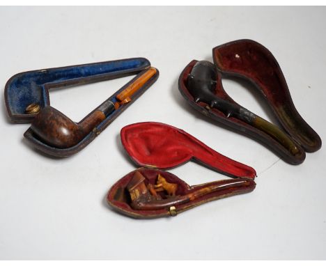 Three cased pipes, one with carved amber novelty bowl, the other two with amber pipe ends, metal mounted, together with a tor