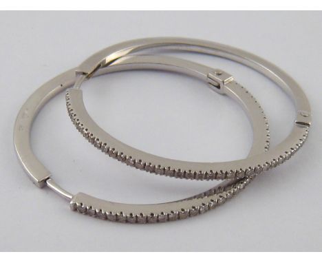 A pair of white metal (tests 18 carat gold) diamond hoop earrings, approx 4cm diameter, estimated total diamond content appro