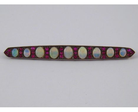 A 15 carat gold opal and ruby brooch, largest opal approx 8 x 6mm, brooch approx 8.2cm long, 8.2 gms, circa 1910.