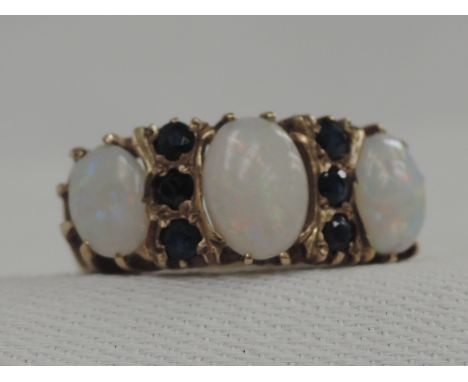 A lady's dress ring having three graduated oval opals interspersed by two rows of sapphire chips in a claw set gallery mount 