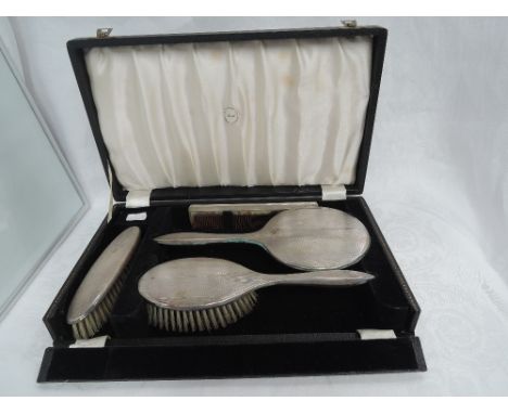 A cased four piece silver dressing table set having engine turned decoration, Birmingham 1950, B & Co