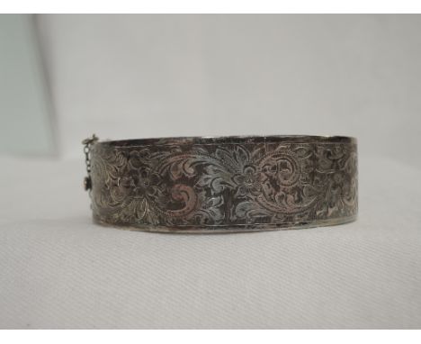 A HM silver hinged bangle having engraved floral and scroll decoration