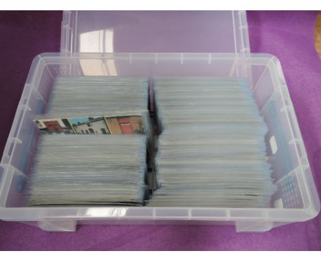 A plastic box containing approximately 600 vintage postcards in sleeves, unsorted