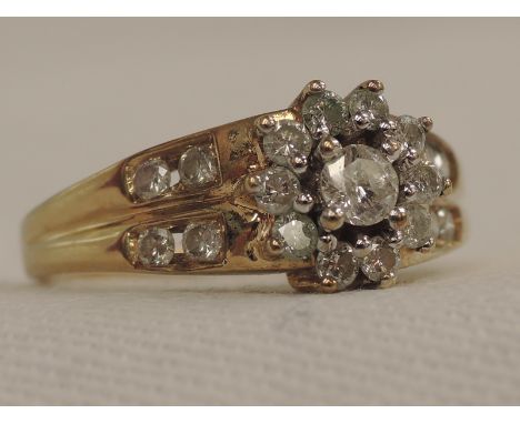 A lady's dress ring having a diamond daisy cluster, flanked by four channel set diamonds to each shoulder, total approx .5ct,