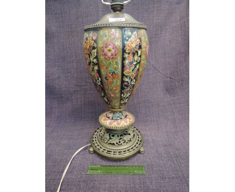 An early 20th century cast metal and ceramic table lamp having coloured enamel decoration on circular base
