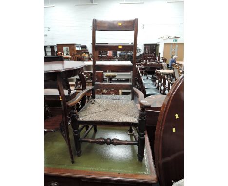 A 19th century stained frame vernacular kitchen armchair having ladder back with rush seats and turned frame