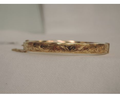 A 9ct gold hinged bangle having engraved scroll decoration,  approx 10.3g