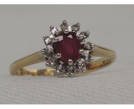 A lady's dress ring having a ruby and diamond chip cluster in a claw set mount on a 9ct gold loop,  size K/L
