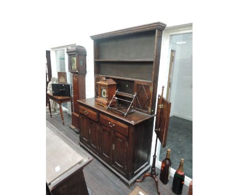 A late 19th century oak dresser in the 18th century style having Delft rack with cupboards over 2 frieze drawers and fielded 