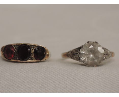 A lady's dress ring having three graduated red gem stones in a closed gallery mount on a rose metal loop, and another dress r