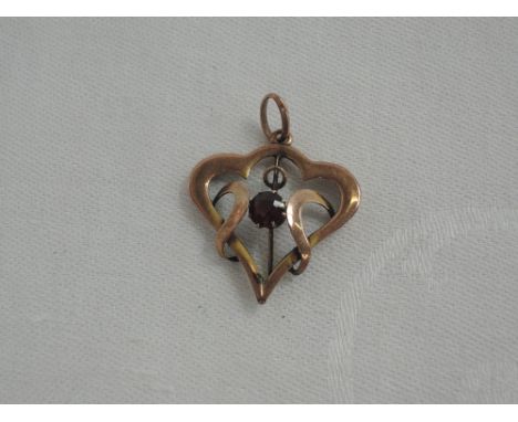 An Edwardian style heart shaped 9ct rose gold heart shaped pendant having a central ruby