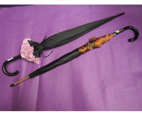 Two lady's walking stick umbrellas, in black with pink frill rim and black with tan alphabet rim