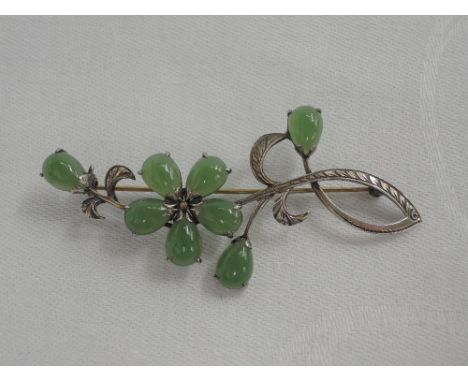 A white metal floral brooch stamped Japan having jade decoration