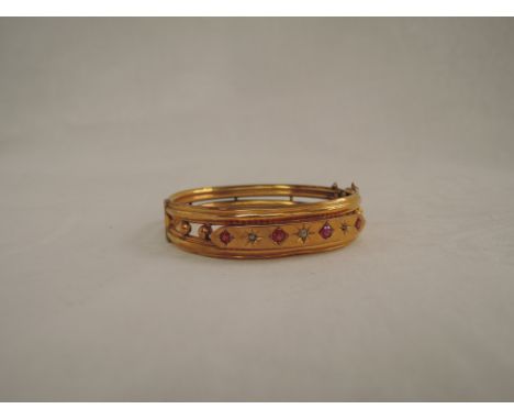 A Victorian yellow metal hinged double bangle stamped 9ct having an old cut diamond and ruby set panel and ball decoration ,(