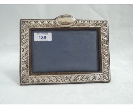 A silver photograph frame having embossed wave decoration and plain oval cartouche with velvet covered easel back, London 198