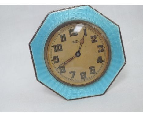 A silver travel clock of octagonal form having turquoise guilloche enamel decoration and an 8 day movement with Arabic numera