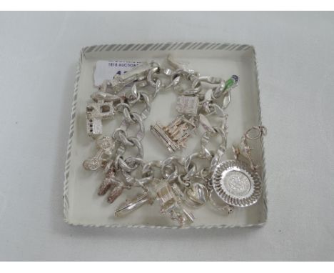 A continental silver heavy curb chain bracelet having 16 white metal charms (3 loose) including speed boat, longcase clock, a