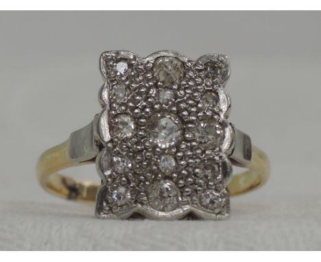 A lady's dress ring having an Art Deco style diamond pave set shaped rectangular panel on a yellow metal loop stamped plat & 
