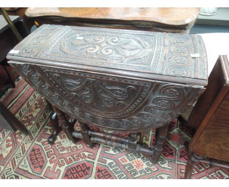 A late Victorian oak drop leaf occasional table having extensive floral carved decoration on bobbin gate legs