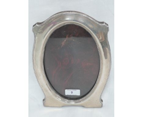 A silver photograph frame of plain shaped oval form with wooden easel back, Chester 1912, J & R Griffin