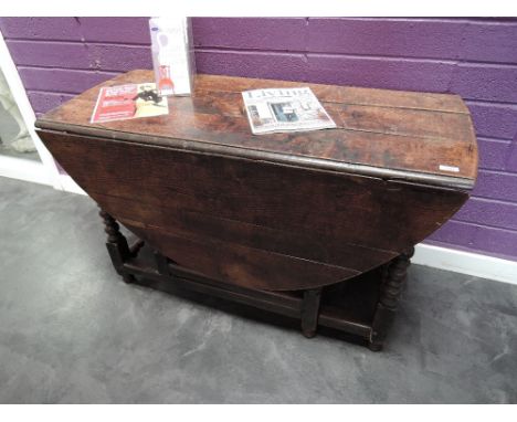 A 19th century oak dining table in the 18th century style having oval drop leaf top with frieze drawer, on bobbin gate legs