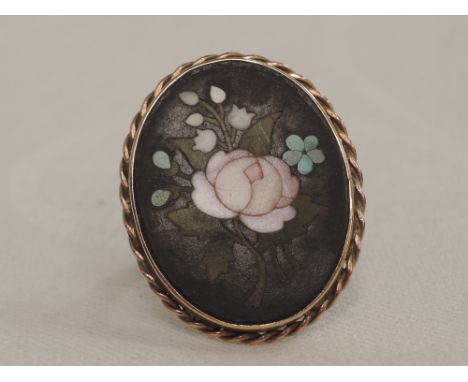 A lady's dress ring having a pietra dura panel in a collared mount on a yellow wire triple loop, no marks tested as 9ct gold,