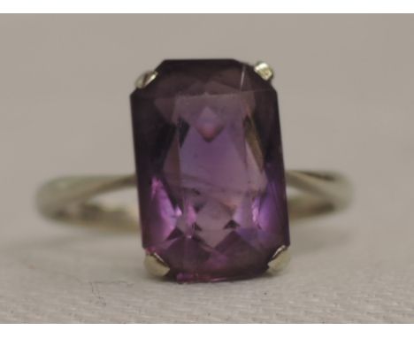 A lady's dress ring having a rectangular amethyst stone in a claw basket mount on a white metal loop stamped 9ct,  size O