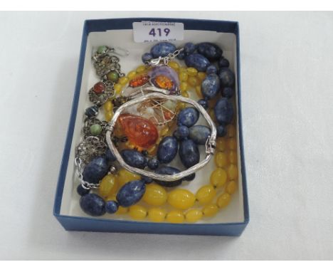 A small selection of costume jewellery including Baltic amber brooch, two strings of beads, silver hinged bangle etc