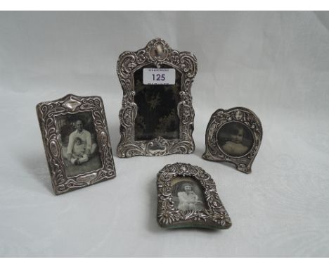 Four HM silver photograph frames having moulded decoration and leather/material cover easel backs