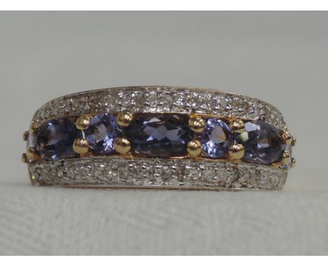 A lady's dress ring having a central row of tanzanite bordered by diamond chips on an 18ct gold loop,  size N