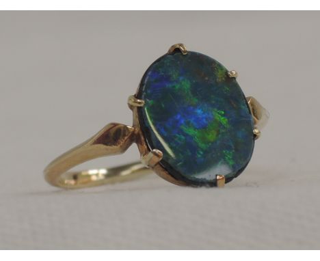 A lady's dress ring having a black opal doublet in a collared claw mount on a yellow metal loop stamped 15ct, size PVery fier