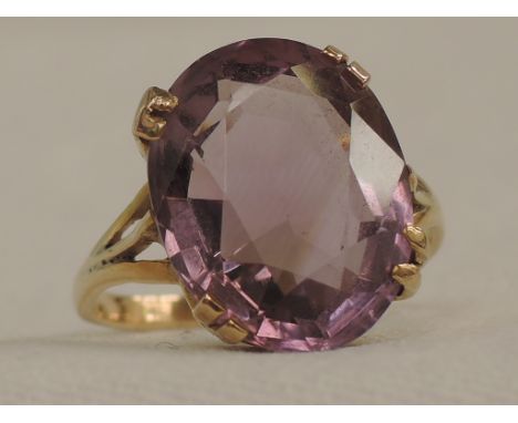 A lady's dress ring having an oval amethyst in a claw set basket mount on a yellow metal loop stamped 9ct,  size N