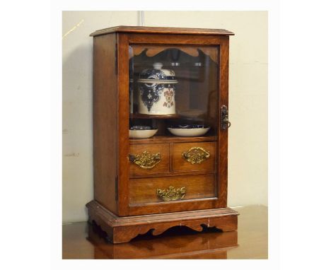 Early 20th Century oak table top smoker's cabinet, the bevelled glazed door enclosing a fitted interior with tobacco jar, two