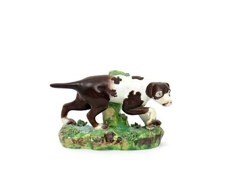 A Staffordshire pearlware model of a pointer dog  early 19th century, standing on a grassy base applied with flowers and leav