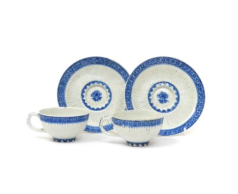 A pair of Bow blue and white cups and saucers  c.1760, with wide bands of reeding enclosed by cell diaper and stiff leaf bord